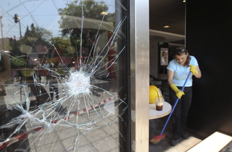 Image: A woman sweeps broken glass in Athens