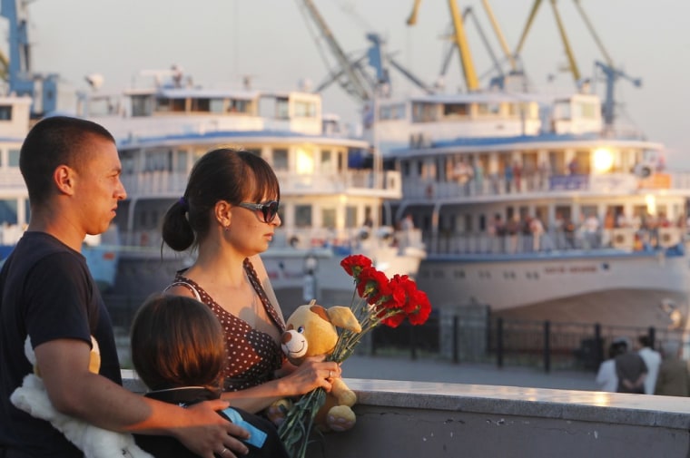 Image: A family brings flowers in memory of victims of the tourist boat \"Bulgaria\", which sank on the Volga river, at the port of Kazan