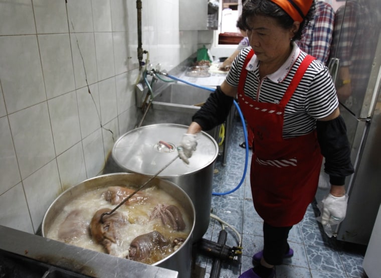 Image: A woman cooks dog meat at a restaurant in Seoul