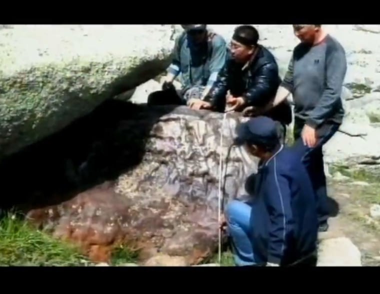Researchers led by Baolin Zhang, a meteorite specialist at the Beijing Planetarium, study a giant meteorite that was found in a mountainous region in northwest China.