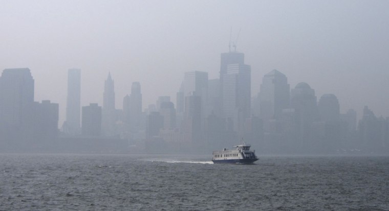 Image: A thick haze hangs over the skyline of Lower Manhattan as a ferry crosses the Hudson River in New York