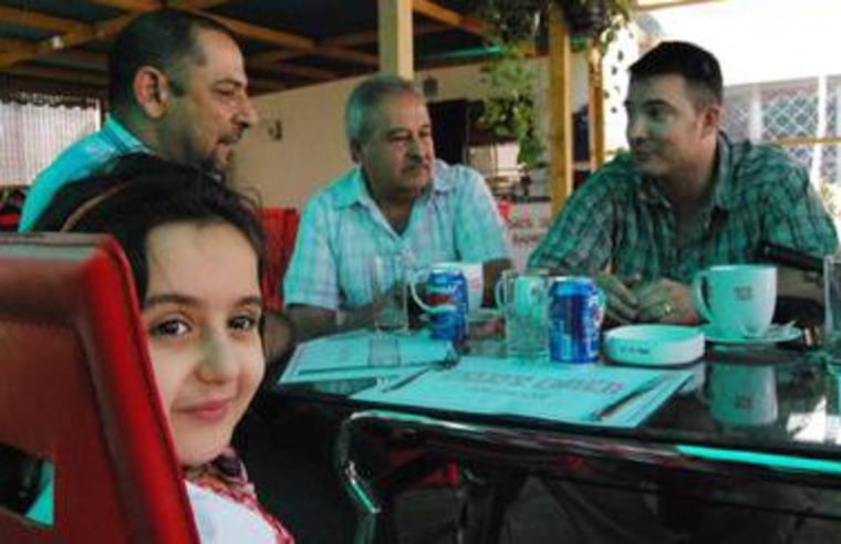 Captain Tom Hickey, right, speaks with Mohammad Adnan with his daughter Sadeel at the table. A colleague of Captain Hickey is between them. Hickey helped save Sadeel's life in 2007 when his soldiers rushed her to hospital after she was shot in the Baghdad neighborhood of Amariyah. 