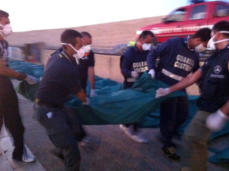 Image: Italian coast guard officials carry a dead body at a harbour in Lampedusa