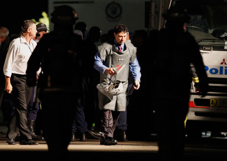 Image: A policeman wearing protective equipment walks near a house in the exclusive Sydney suburb of Mosman