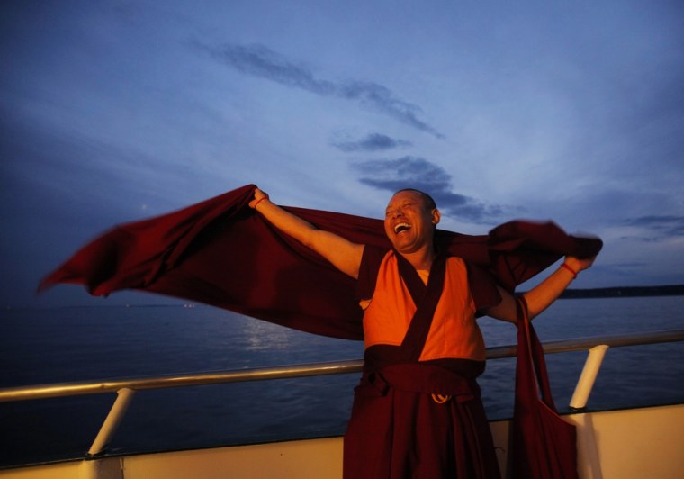 Image: A Buddhist monk laughs during the release of lobsters back into the ocean on \"Chokhor Duchen\" in the waters off Gloucester