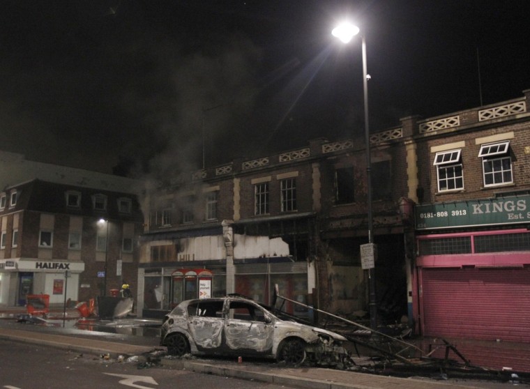 Image: A destroyed car is seen on a street in Tottenham