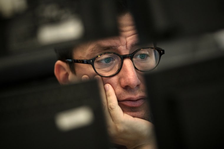 Image: A stock broker works behind computer monitors at the stock exchange in Frankfurt, Germany