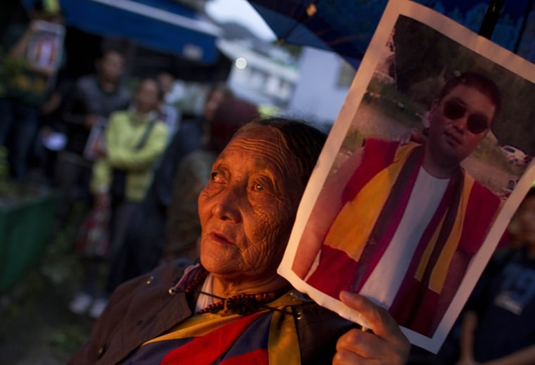 Image: A tibetan holds a portrait of Tsewang Norbu