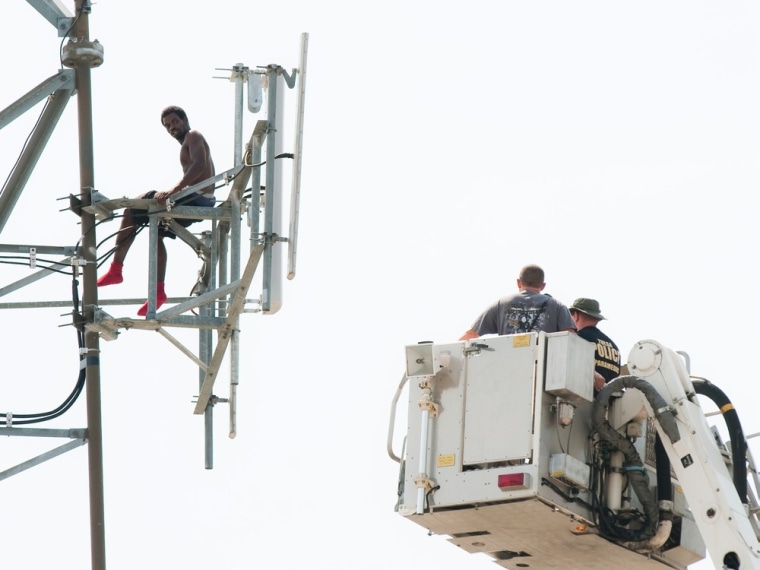 Image: Negotiators in a ladder truck attempt to persuade the man on the Clear Channel Communications broadcast tower