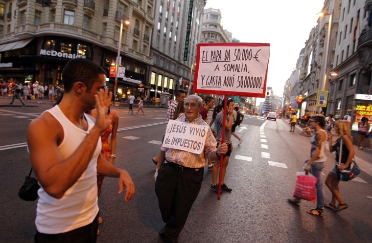 Image: A man holds and wears signs on the first day of the World Youth Day meeting in Madrid