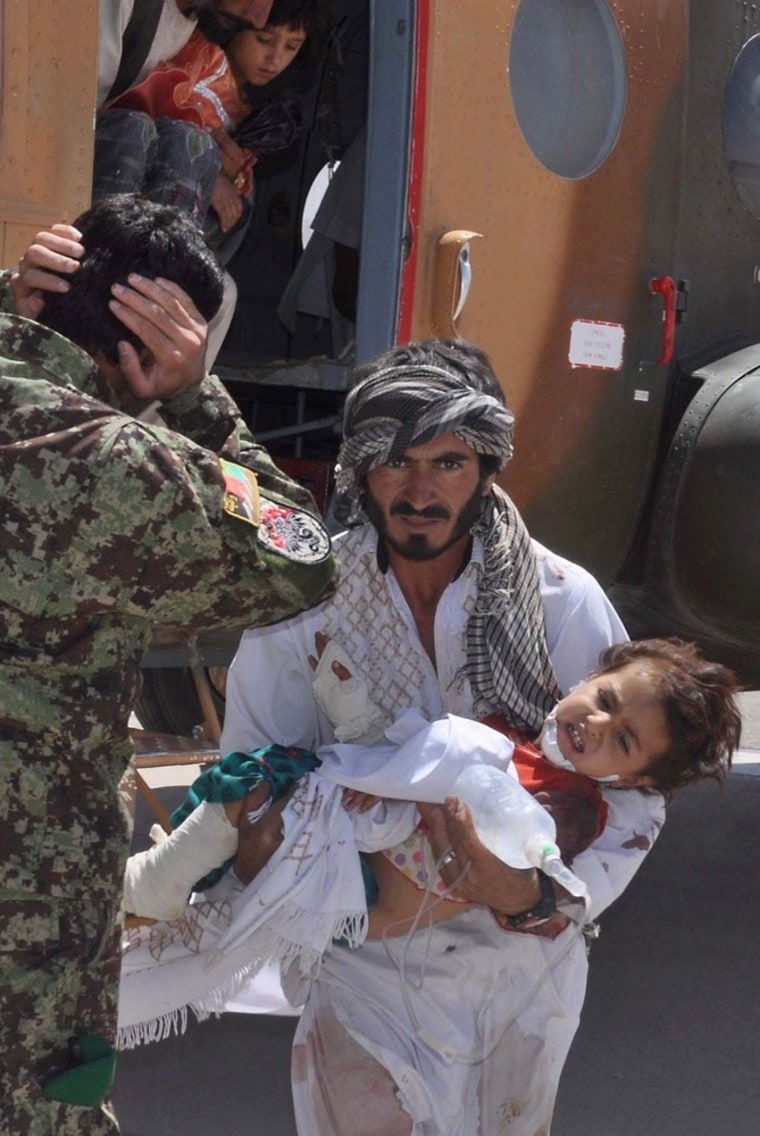 Image: An Afghan man carries an injured child from a heilicopter, after the boy was injured by a roadside bomb in Herat
