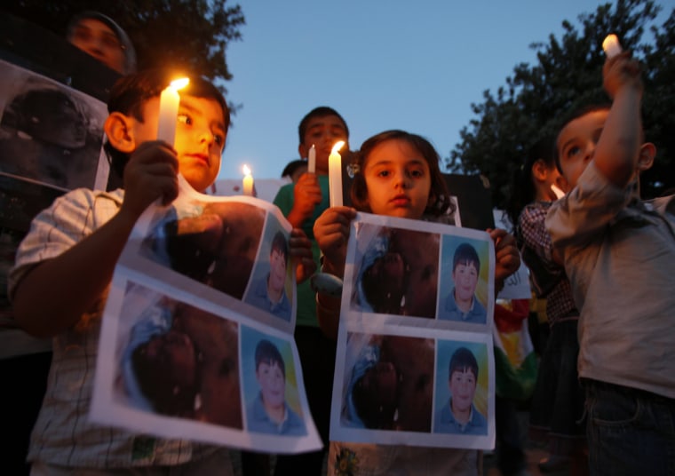 Image: Syrian children carry pictures of Syrian boy Hamza al-Khatib and hold candles during a protest in front of the United Nations building in Beirut