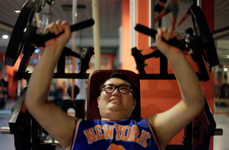 Image: A man lifts weight as part of his training during a six-week programme in an exercise room at the Bodyworks weight loss campus in Beijing