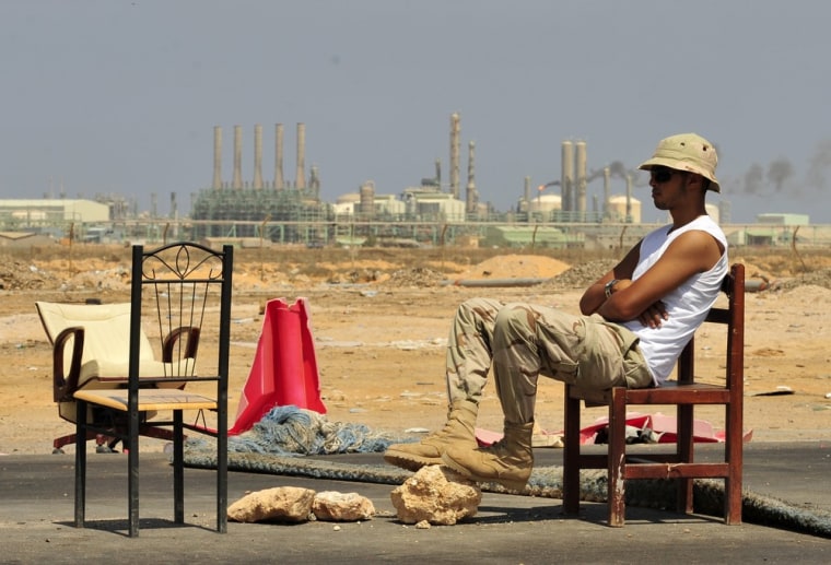 Image: A Libyan rebel fighter sits on an office chair close to a checkpoint at the entrance of the oil port city of Ras Lanuf