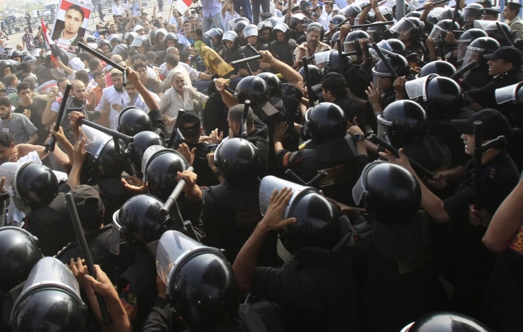 Image: Riot police clash with anti-Mubarak demonstrators in front of the police academy where former Egyptian president Hosni Murbarak is on trial in Cairo