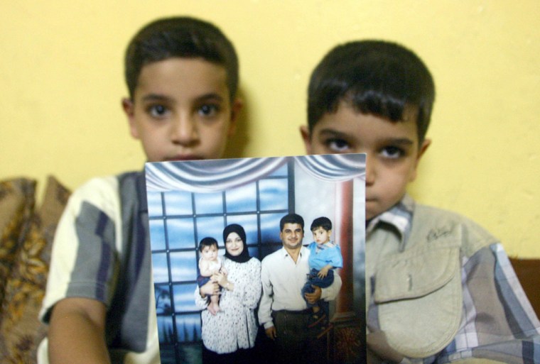 Image: This file picture taken on July 20, 2005 shows Hassan (L) sitting with his younger brother Ali as they show off a family photo of them posing with their father Baha Mousa and their mother, at their home in Basra, 500 kms south of Baghdad.