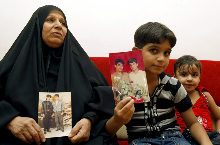 Image: The mother and son of Baha Mousa (R in the picture), an Iraqi hotel receptionist who was kicked and beaten to death whilst in British Army custody, hold pictures of him at their house in Basra