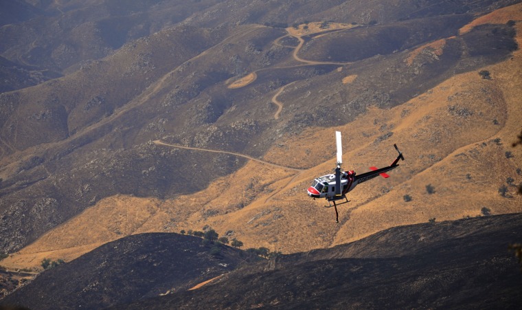 Image: Helicopters fly over the burnt area around Stallion Springs, Calif.
