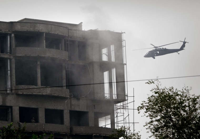 Image: A military helicopter belonging to coalition forces flies around a building during a gun battle with Taliban militants in Kabul