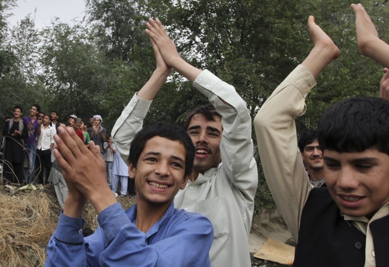 Image: Afghan youth cheer after a building was cleared of militants in Kabul