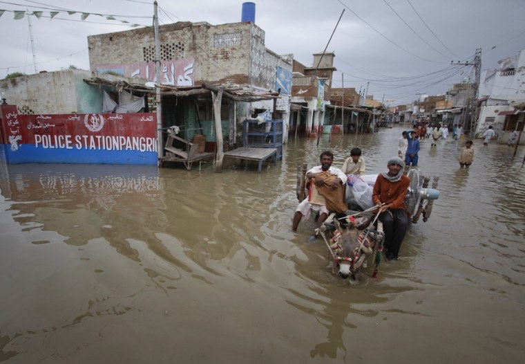 Image: Residents use a donkey cart to carry their belongings out of the flooded streets of Pangrio