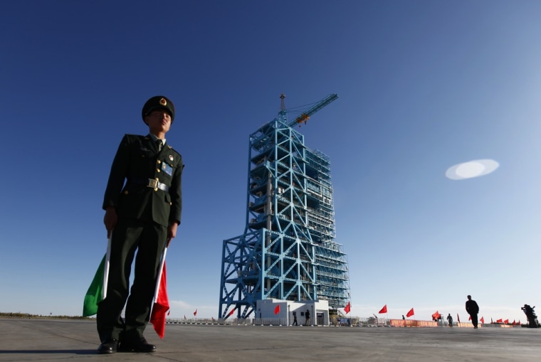 Image: Chinese soldier stands beside Long March II-F rocket loaded with China's unmanned space module Tiangong-1 at the launch pad in the Jiuquan Satellite Launch Center