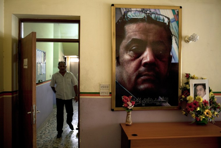 Image: Artificial flowers and two pictures of Hadi al-Mahd, a murdered journalist, accompany the corridor of the radio compound where he hosted a popular radio show in Baghdad.