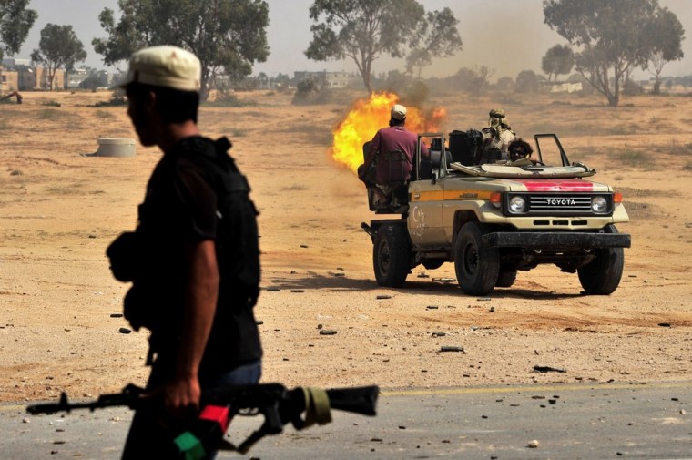 Image: A National Transitional Council (NTC) fighter fires towards a position of loyalist forces in Moammar Gadhafi's hometown of Sirte