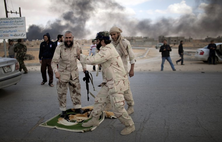 Image: Libyan fighters step on a rug with the image of Moammer Gadhafi outside Bani Walid, Libya.