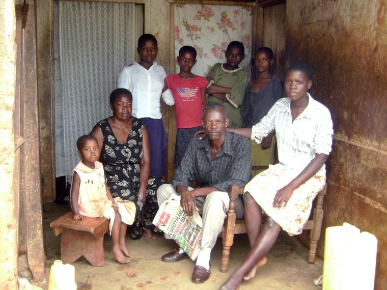 Image: Ahmed Kasadha, center foreground, on the porch of his house in Iganga, Uganda, with one of his wives and six of his 14 children.