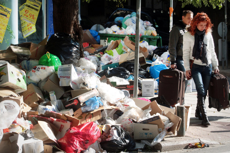 Image: People pass by piles of garbage