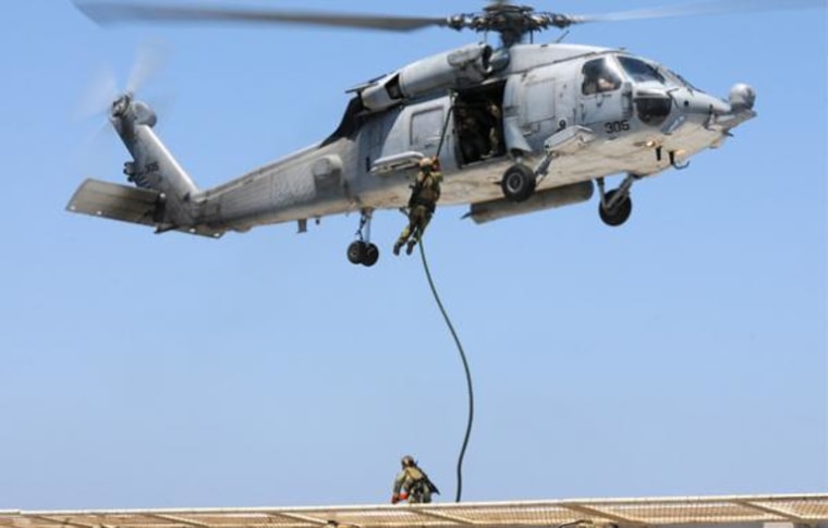 Image: U.S. Navy SEAL fast ropes from helicopter