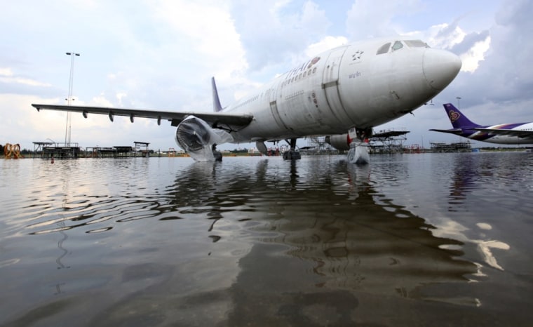 Image: The engines of Thai Airways airplanes are protected as floods advanced at the Don Muang airport in Bangkok