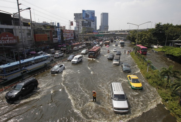 Image: A traffic policeman directs traffic along a flooded street at Lat Phrao district in Bangkok
