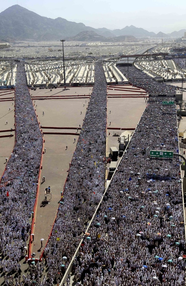 Image: A crowd of Muslim pilgrims make their way to throw cast stones at a pillar, symbolizing the stoning of Satan