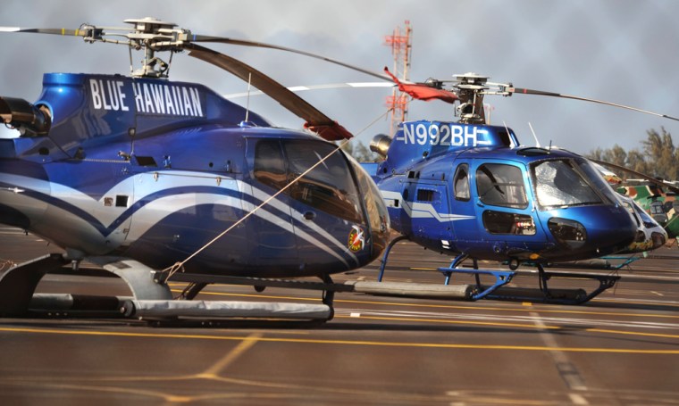 A pair of Blue Hawaiian tour helicopters sit grounded on a tarmac at Kahului Airport in Maui, Hawaii, Thursday afternoon, after a helicopter from the company crashed.