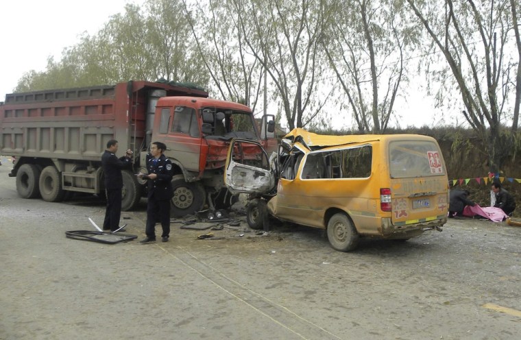 Image: Policemen inspect a school bus and a truck which collided as rescuers pull out a body at a traffic accident site in Gansu Province, China.