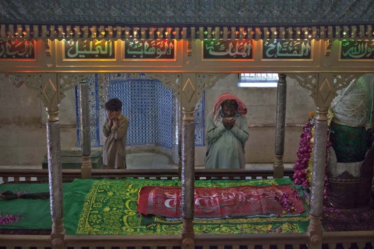 Image: Worshippers pray at the grave of Sufi Saint Abdullah Shah Ashabi in Thatta district, in Pakistan's Sindh province