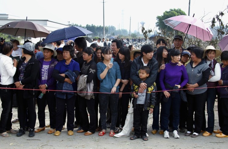Image: Residents of the village of Wukan in Lufeng county, Guangdong province line the main road to welcome the government officials back into the village