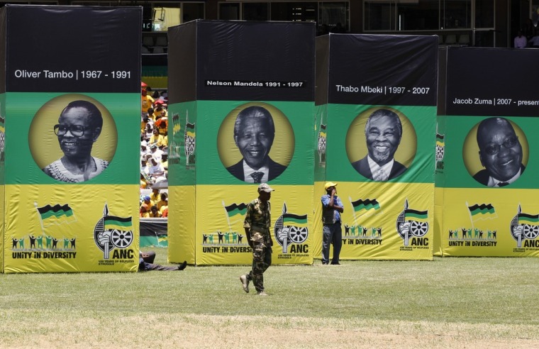 Image: A man in military uniform walks in front of posters depicting faces of former ANC presidents