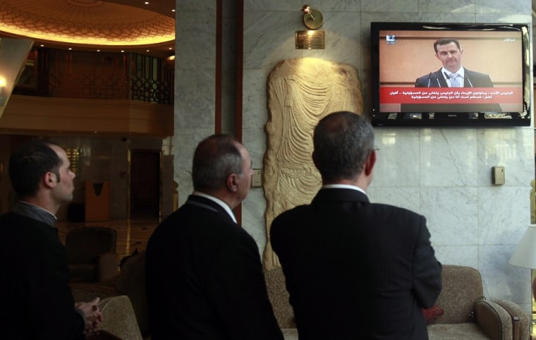 Image: Syrians watch on TV Syrian President Bashar Assad making a speech