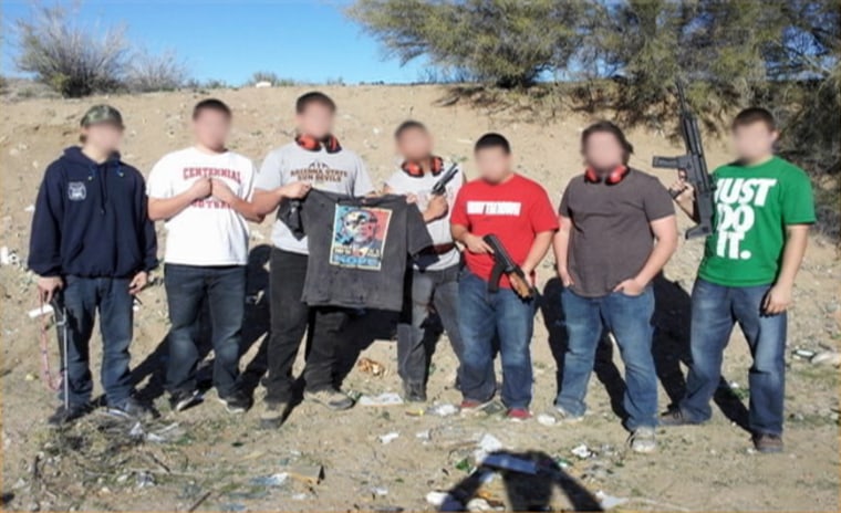 Image: Photo showing a group of men with guns posing with a bullet-ridden image of Barack Obama's face and posted on Facebook.