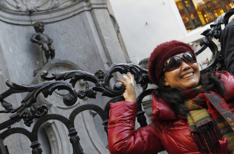 Image: A tourist poses for a photograph in front of Brussels' famous Manneken-Pis statue in central Brussels