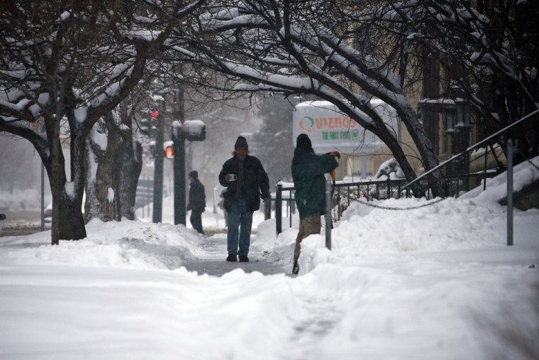 Image: Residents make their way down a snow-packed sidewalk in Denver