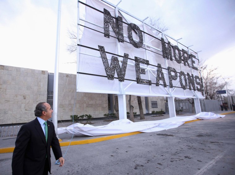 Image: Mexican President Felipe Calderon glances behind after unveiling a banner reading \"No More Weapons\" during an event next to the US border
