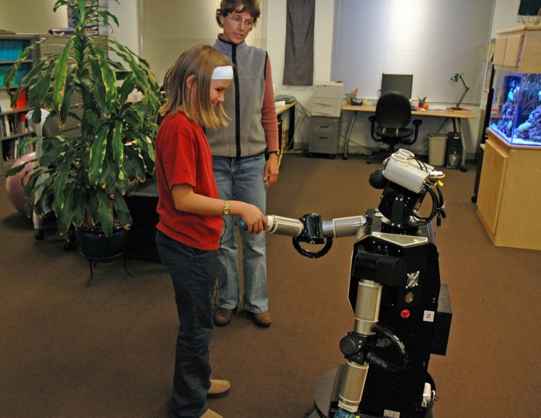 A child interacts with Robovie, a remotely controlled humanoid robot. In the near future, children may view such robots as friends.