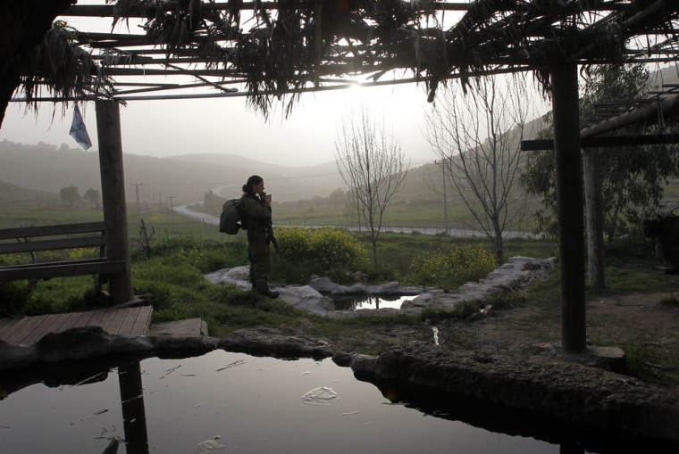 Image: A female Israeli soldier stands next to a man-made pool containing water from a spring located near near Ramallah