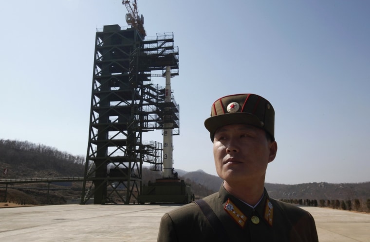 Image: A soldier stands guard in front of the Unha-3 (Milky Way 3) rocket sitting on a launch pad at the West Sea Satellite Launch Site, during a guided media tour by North Korean authorities in the northwest of Pyongyang