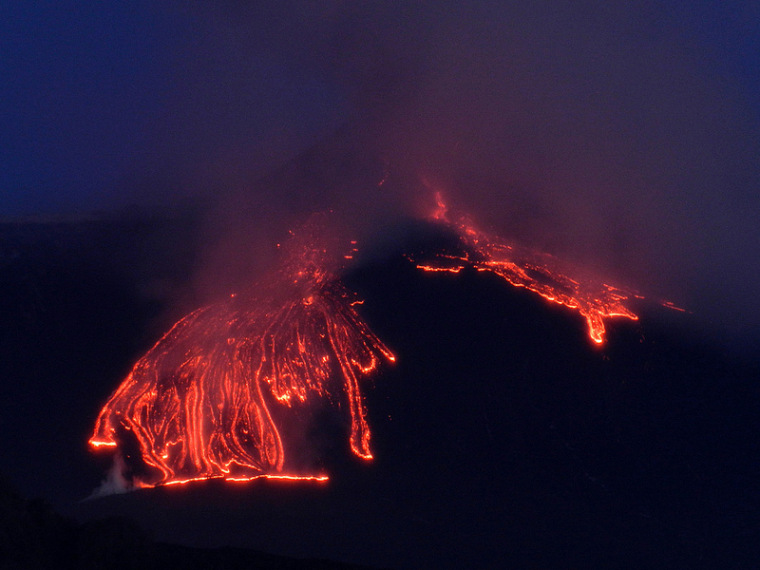 Glowing rivulets of lava run down Mount Etna's flanks as dawn begins to break.
