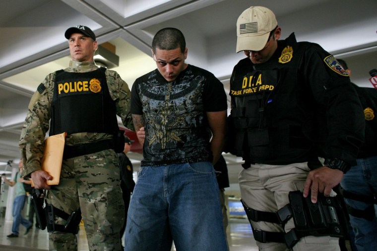 Image: Drug Enforcement Administration officers escort a handcuffed suspect after his arrest on drug smuggling charges in San Juan, Puerto Rico